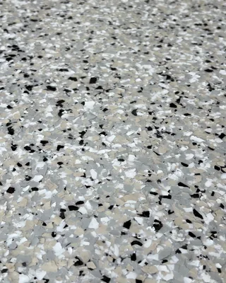 Close-up of tan, gray, white and black flakes in a glossy floor.