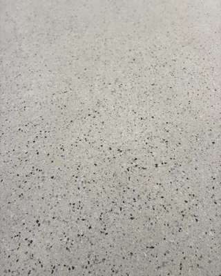 Close-up of a light gray floor finish with fine black, gray and white flecks.
