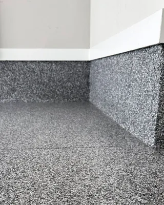 Garage corner where the gray, black and white flake floor continues up the stem walls to the white wall trim.