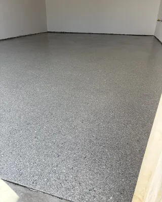 Empty room with a glossy gray speckled floor and plain white walls.